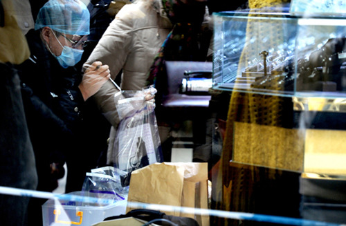 A police officer examines the starter pistol believed to have been used by two men when they robbed a jewelry store in Feidong county of Anhui province on Saturday. [Ma Qibing/For China Daily]