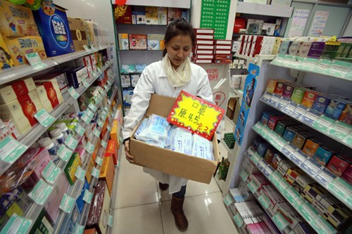 A staff member at a pharmacy in Beijing sets out a display of masks on Sunday. [Wu Hailang/For China Daily]