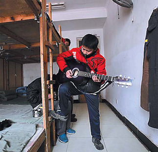 A boy plays guitar in a dormitory room at the boarding school. 