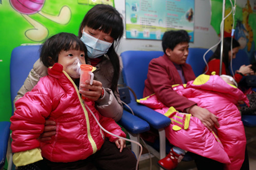 Wang Ruoqi (left), a 2-year-old girl, inhales medicine to treat her bronchitis at the pediatric department of China-Japan Friendship Hospital in Beijing on Tuesday. [Feng Yongbin/China Daily]