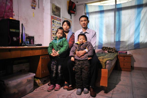 Migrant worker Gao Changliang (L), his wife Gao Qingfang, daugther Gao Zihan, and son Gao Zihao pose for a picture in a rented room in Guangzhou, Guangdong province on Jan 21, 2013 before going back to their hometown in Anyang, Henan province for the Spring Festival. [Photo/Xinhua]