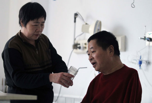 Mao Dahua cares for her husband Liu Jingsheng, an armless Beijing artist, at a hospital in the city on Saturday. Suffering from kidney failure and unable to undergo dialysis, Liu is looking for kidney donation to save his life. [ZHU XINGXIN / CHINA DAILY]