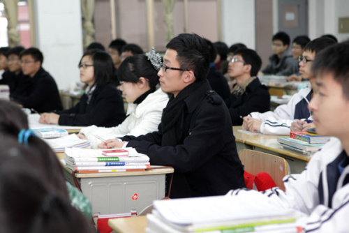 Anhui native Liu Peng (right) takes notes in class in a private high school in Zhejiang province. He no longer needs to spend extra time studying textbooks used in his hometown after the province's new gaokao rules allow students without local hukou to attend the entrance exam in Zhejiang. [LUO SHANXIN / FOR CHINA DAILY] 