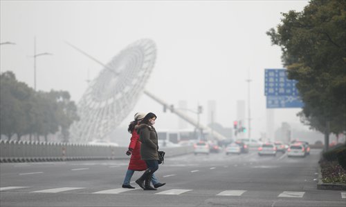 Residents cross the street Thursday in Pudong New Area with masks to filter out the pollution. Photo: Yang Hui/GT 