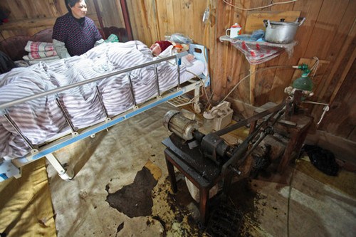 Fu Xuepeng with the self-made ventilator, as his mother Wang Lanqin looks on. Fu's parents have kept their son alive for more than five years using the ventilator. [Pan Kanjun / for China Daily]