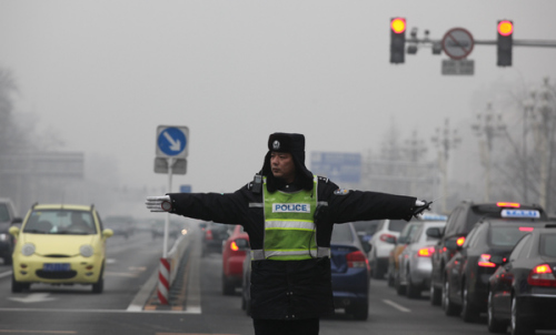 A traffi c policeman on duty at a crossing at Dongdan in Beijing on Wednesday. Traffi c police in China's smog-covered cities are waiting for offi cials to cut the red tape that bars them from wearing protective facemasks while on duty. [WANG JING / CHINA Daily]