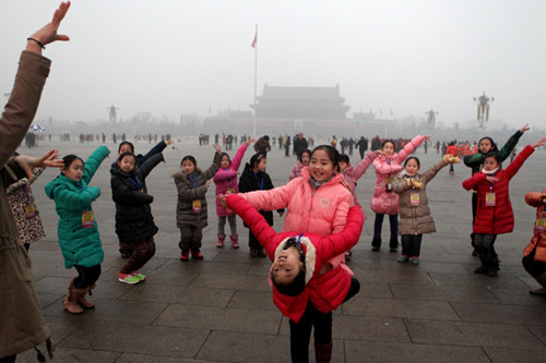 Children from a primary school in Xuzhou, Jiangsu province, dance at smoggy Tian'anmen Square in Beijing on Thursday. [Zhu Xingxin / China Daily]