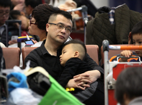 The much-anticipated journey home can entail a great deal of waiting at train stations and airports, as these images prove. Hopeful travelers at Beijing Railway Station on Sunday had weighty matters of baggage to consider while at Beijing Capital International Airport sleep was an option, at least for the very young. [PHOTOS BY WANG JING AND DU LIANYI / CHINA DAILY]