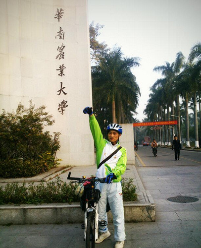 Sun Shaogang in front of the gate at South China Agricultural University in Guangzhou, Guangdong province, on Jan 15, when he started a trip home to Yunnan province by bicycle. [PROVIDED TO CHINA DAILY]