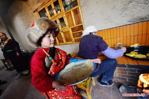 A Tibetan girl carries dough cakes to be fried for Tibetan New Year in Xiapai Village at Guide County, northwest China's Qinghai Province, Feb. 6, 2013. The Tibetan New Year, or Losar, falls on Feb. 11 this year. (Xinhua/Wu Gang)