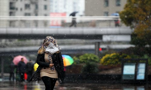 A gust of wind grabs a woman's scarf as she walks through the snow at Shanghai Railway Station Thursday. Weather forecasters have predicted that the city will receive a white Chinese New Year. Photo: Yang Hui/GT 