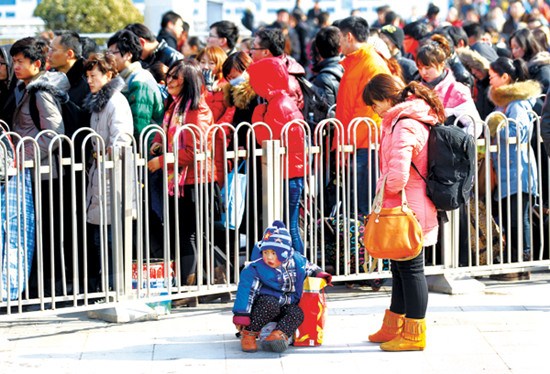 People returning to Beijing after spending the Spring Festival holiday at their hometowns line up to take the subway at the Beijing Railway Station on Friday. [Zou Hong / China Daily]