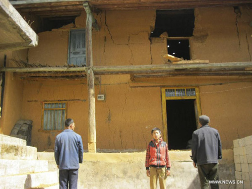 Villagers stand in front of a building struck by earthquake in Qiaojia County of Zhaotong City in southwest China's Yunnan Province, Feb. 19, 2013. Two people were injured when a 4.9-magnitude quake jolted the border area of southwest China's Sichuan and 