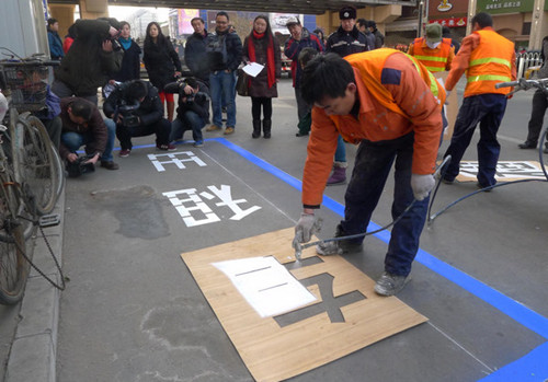 Traffic management officers mark the sign of an exclusive parking space for taxis in Beijing on Monday. Nearly 50 such spaces are planned for 16 locations where people say it is often difficult to hail a cab. Taxi drivers can park for free. [Wu Ning / for China Daily]