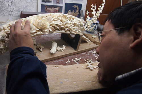 An artist carves a piece of ivory at the Beijing Ivory Carving Factory in January. [Yang Yao / China Daily]