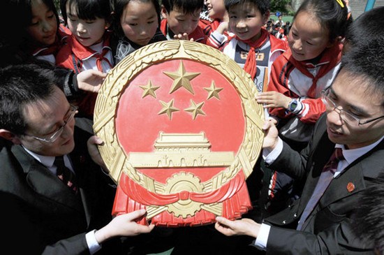 Judges tell primary school students in Dayang township, Chongqing, about the national emblem to help them establish awareness of the rule of law. [RAO GUOJUN / FOR CHINA DAILY]