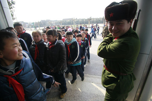 Dressed like Lei Feng, a parent stands guard for the 600 students at a primary school in Jinan, Shandong province, on Tuesday, Learn from Lei Feng Day. Lei (1940-62), a Chinese soldier is known for selflessly helping people in need. [For China Daily]