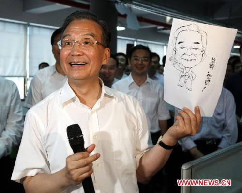 Chinese Premier Wen Jiabao smiles while showing a cartoon presented by a worker in Talkweb Information System Co., Ltd. in Changsha, capital of central China's Hunan Province, on July 2, 2010. Wen Jiabao made an inspection tour to Changsha recently. (Xinhua File Photo/Yao Dawei)