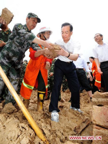 Chinese Premier Wen Jiabao (front R) cleans ruins with rescuers in Shuangshang village in Cangwu County of southwest China's Guangxi Zhuang Autonomous Region, June 20, 2010. Wen Jiabao inspected flood-affected area in Guangxi from June 19 to 20. (Xinhua File Photo/Li Tao)