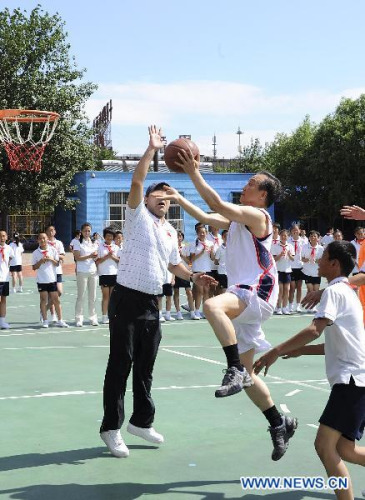 Chinese Premier Wen Jiabao joins a basketball training in the Shibalidian Primary School in Beijing's Chaoyang District, May 31, 2011. Wen took part in a 40-minute basketball training session here with a group of pupils Tuesday in Beijing, encouraging Chinese children to keep themselves healthy by participating in sports and other physical activities. (Xinhua File Photo/Rao Aimin)