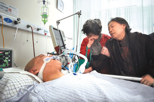 Family members watch over Song Yang, a bus driver in Shandong province, in Second Hospital of Shandong University. On Saturday, Song managed to pull over on an expressway before falling into a coma. He is in a critical condition. [CHINA DAILY]