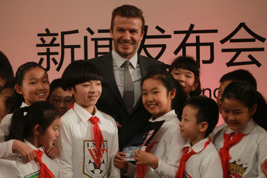 David Beckham poses with students after a press conference in Shi-Jia Primary School in Beijing on March 20, 2013. [Cui Meng/chinadaily.com.cn]