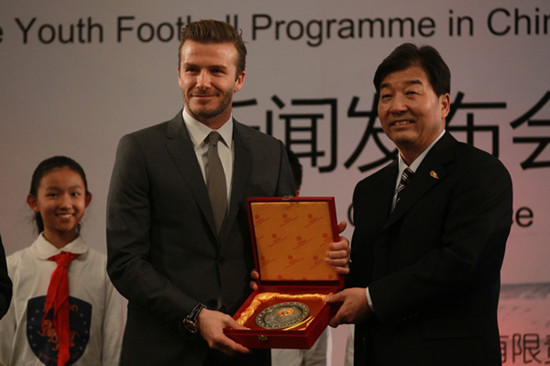 David Beckham recieve a gift from Wei Jixiang, a soccer official with China's General Adminstration of Sports, after a press conference in Shi-Jia Primary School in Beijing on March 20, 2013. [Cui Meng/chinadaily.com.cn] 