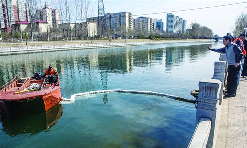 Cleaners attempt to mop up the oil in Kunyu River Sunday. Photo: Li Hao/GT