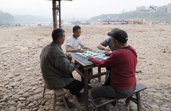 People in Chongqing play mahjong on a dried-up riverbed on Monday. Many riverbeds in the Chongqing section of the Jialing River have become places of amusement for local people. CHEN CHAO / CHINA NEWS SERVICE