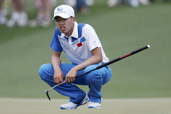 Fourteen-year-old Guan Tianlang of China (R) hits his approach shot to the first green next to caddie Brian Tam (L) during first round play in the 2013 Masters golf tournament at the Augusta National Golf Club in Augusta, Georgia, April 11, 2013.  [Photo/Agencies]