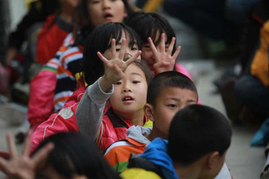 A group of children play games at a psychological aid site in Lushan county, Sichuan province, on Tuesday. Through the training, volunteers want to encourage the children to be optimistic and confident. CUI MENG / CHINA DAILY  