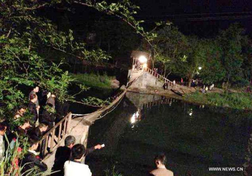 Photo taken on May 2, 2013 shows the tilted suspension bridge in Fenghuang County , central China's Hunan Province. About 40 people, who returned from a bonfire  party, were on the bridge when the bridge floor suddenly tilted in Fenghuang at around 9:10 p.m. on May 1, and more than 20, including children and elderly people, fell into the 1.2-meter-deep river water. (Xinhua/Tian Jiwei) 