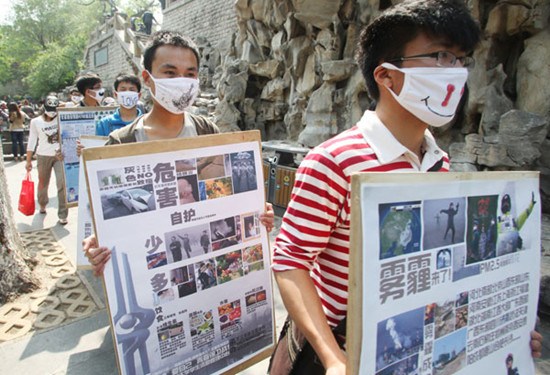 Students of Shandong Jianzhu University remind people of environmental protection by wearing masks and holding billboards on Sunday in Jinan, capital of Shandong province. Zheng Tao / For China Daily