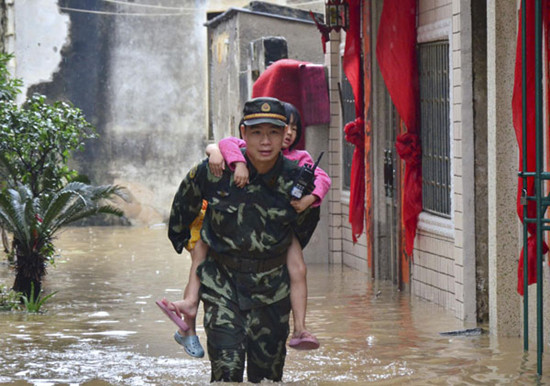 A police officer carries a girl to safety after a village is flooded in Shanwei city, South China's Guangdong province, on May 9. [Photo/Xinhua] 