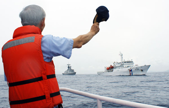 An official waving his cap as a fleet of naval and coast guard frigates set sail from Taiwan's southern port of Kaohsiung. Taiwan on Sunday dispatched four coast guard and naval vessels to beef up patrols in waters near the Philippines following public outrage over the shooting of a fisherman by Filipino coast guards. TAIWAN'S COAST GUARD via Agence France-Presse