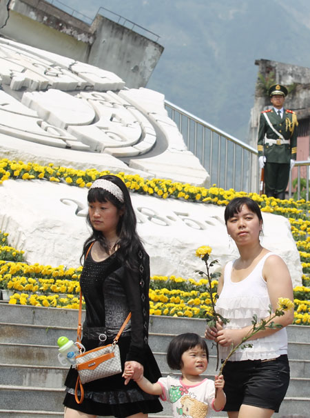 Yang Zhenrong, 42, (left), mourns her 12-year-old son, who was killed in the massive earthquake five years ago, with her 2-year-old daughter, at what remains of Xuankou High School in Yingxiu township, Wenchuan county, in Sichuan province, on Sunday. Zhu Xingxin / China Daily