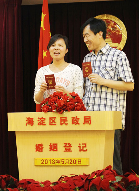 Newlyweds pose with their marriage license at the marriage registration office of civil affairs bureau of Haidian district in Beijing on Monday. Zhu Xingxin / China Daily