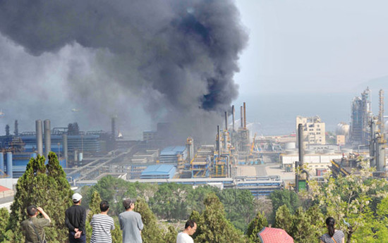 Residents look on after two diesel tanks exploded at an oil refinery of China National Petroleum Corporation in Dalian on Sunday afternoon. The fire was extinguished at 4 pm, but smoke from the blaze raised pollution concerns among residents. Liu Debin / For China Daily