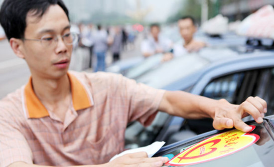 A cab driver pastes a free for gaokao students sticker on his windshield in Chongqing on Thursday. CHEN SHICHUAN / FOR CHINA DAILY