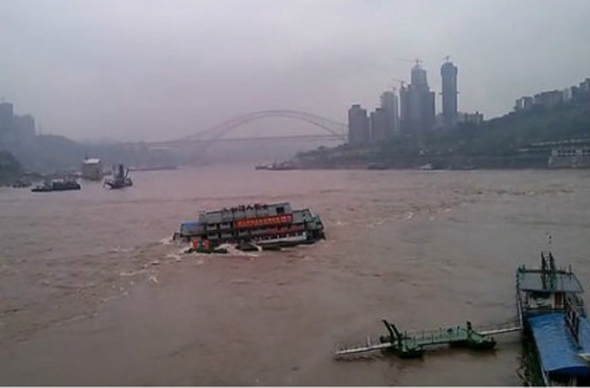 A barge is seen capsized in the river in southwest China's Chongqing Municipality. The barge was washed away from shore after water levels suddenly rose Monday morning. (Photo from weibo.com)