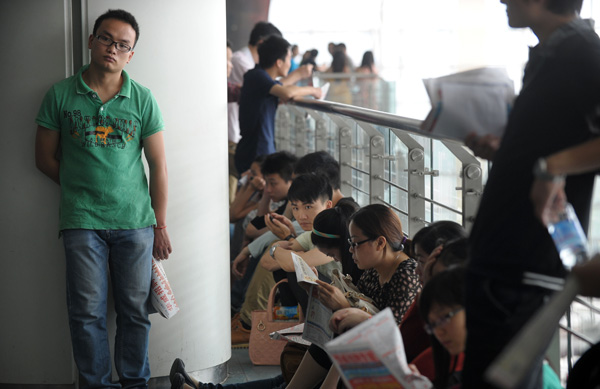 College graduates take a break at a job fair in Chongqing in May. The fair offered 20,000 vacancies at 500 businesses. Yu Xiao / for China Daily