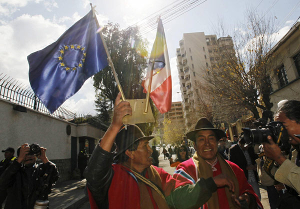 An Aymara man holds the flags of the European Union and France after removing them from the wall of the French embassy in La Paz, in protest against the French government's ban of Bolivian President Evo Morales' plane in its airspace, July 3, 2013.[Photo/Agencies]