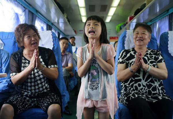 Xiang Jinyue, 7, sings as she travels with her grandparents on the Kunming-Mengzi train. Photo by Feng Yongbin / China Daily