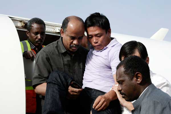 A Chinese worker (center), who was abducted by Darfur rebels in January, is helped off the plane upon his arrival at the Khartoum airport in Sudan after his release on Jan 17. Four workers with China Railway 18 Bureau Group Co were abducted by Darfur rebels on Jan 12 and freed five days later. EBRAHIM HAMID / AFP PHOTO  