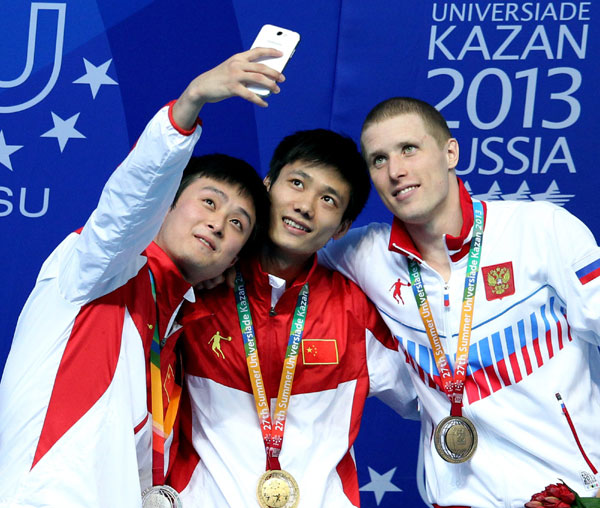 Gold medalist Lin Jin, center, silver medalist Qin Tian of China and bronze medalist Evgenii Novoselov, right, of Russia pose for a photo on the podium of the men's 1 meter springboard final at the Kazan Universiade in Kazan, Russia, July 9, 2013. [Photo/Xinhua]