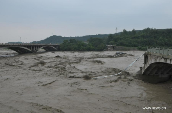 Photo taken on July 9, 2013 shows the collapsed old Qinglian Bridge (R) across the Tongkou River in Jiangyou City, southwest China's Sichuan Province. The neighboring bridge on the left is the Qinglian Bridge. An unknown number of vehicles and pedestrians fell into the river after the bridge collapsed on the morning of July 9. The water level of the river rose significantly over the past two days due to continuous rainfalls in the region. (Xinhua) 