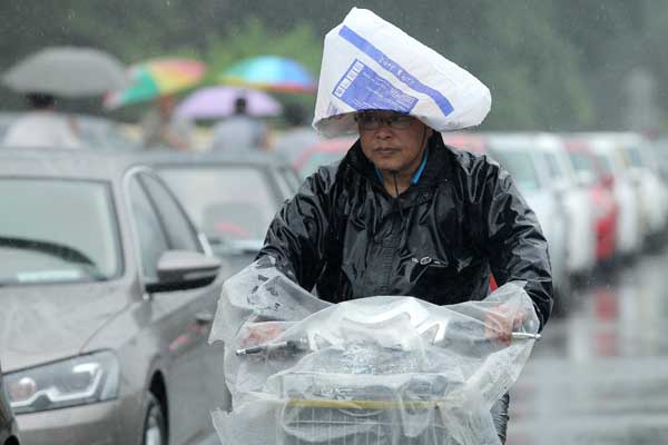 A Beijing resident wears an improvised hat in the rain on Monday. According to the Beijing Water Authority, an average of 45.9 millimeters of rain fell on the city from 8 pm Sunday to 11 am Monday. Wang Jing / China Daily