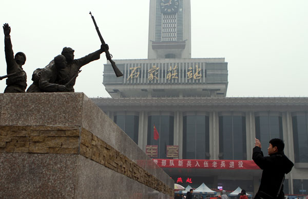 A visitor takes a photo of a sculpture that stands in front of the city's old railway station. [Photo Provided to China Daily]