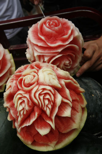 Flowers are carved into watermelons by Zhang Yunxiao, a 30-year-old fruit seller, July 22, 2013. [Photo/Asianewsphoto]