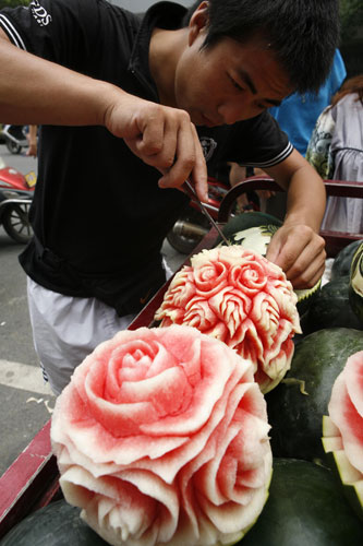 Zhang Yunxiao, a watermelon seller in Xiangyang, Central China's Hubei province, carves flowers onto a watermelon, July 22, 2013. Prices for the carved watermelons range from 20 yuan ($3.26) to 50 yuan. [Photo/Asianewsphoto]